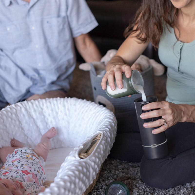 The Keddle portable breast milk bottle warmer with mom pouring in baby formula.